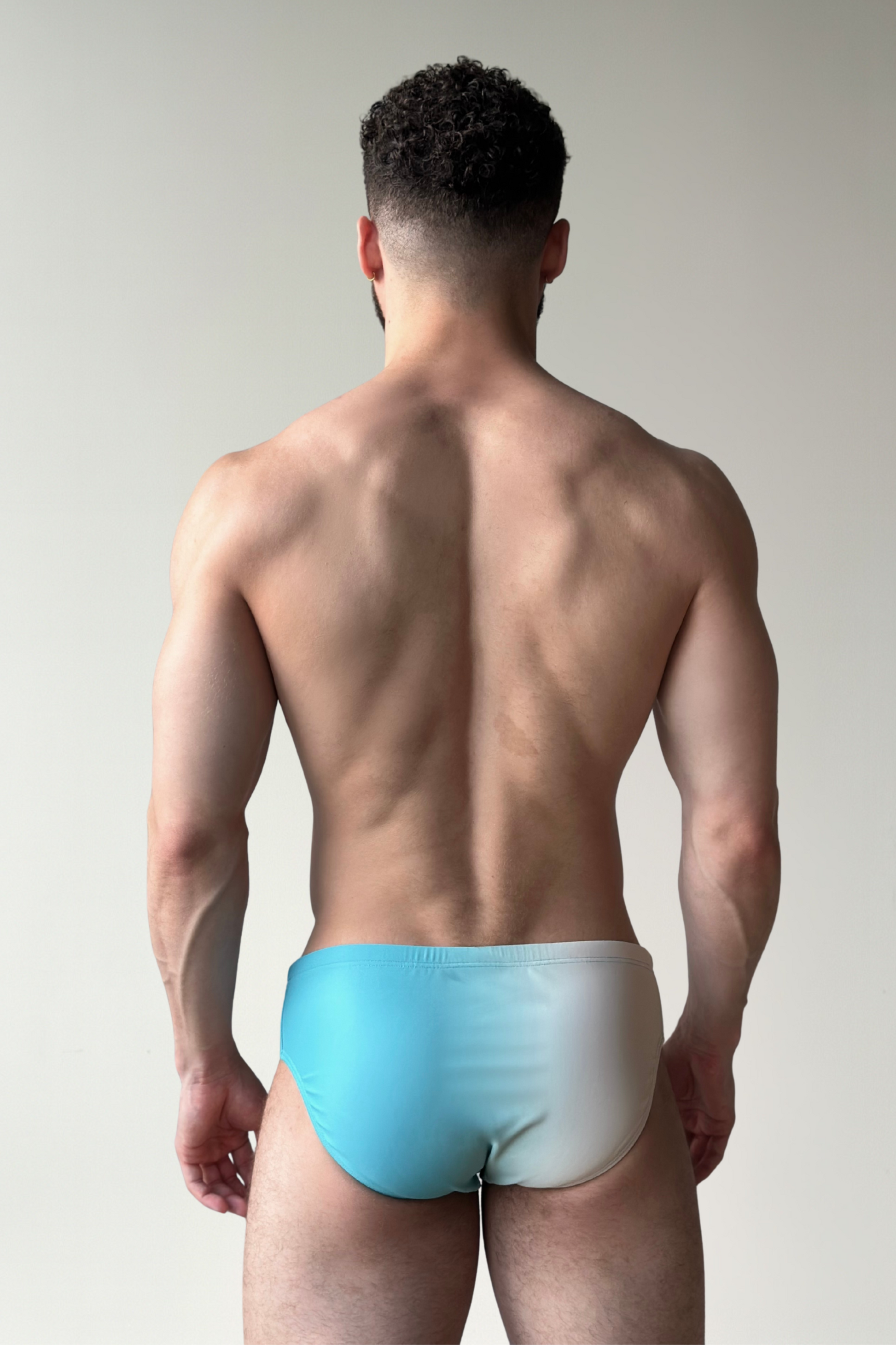 Man wearing a colorful swim brief against a plain background