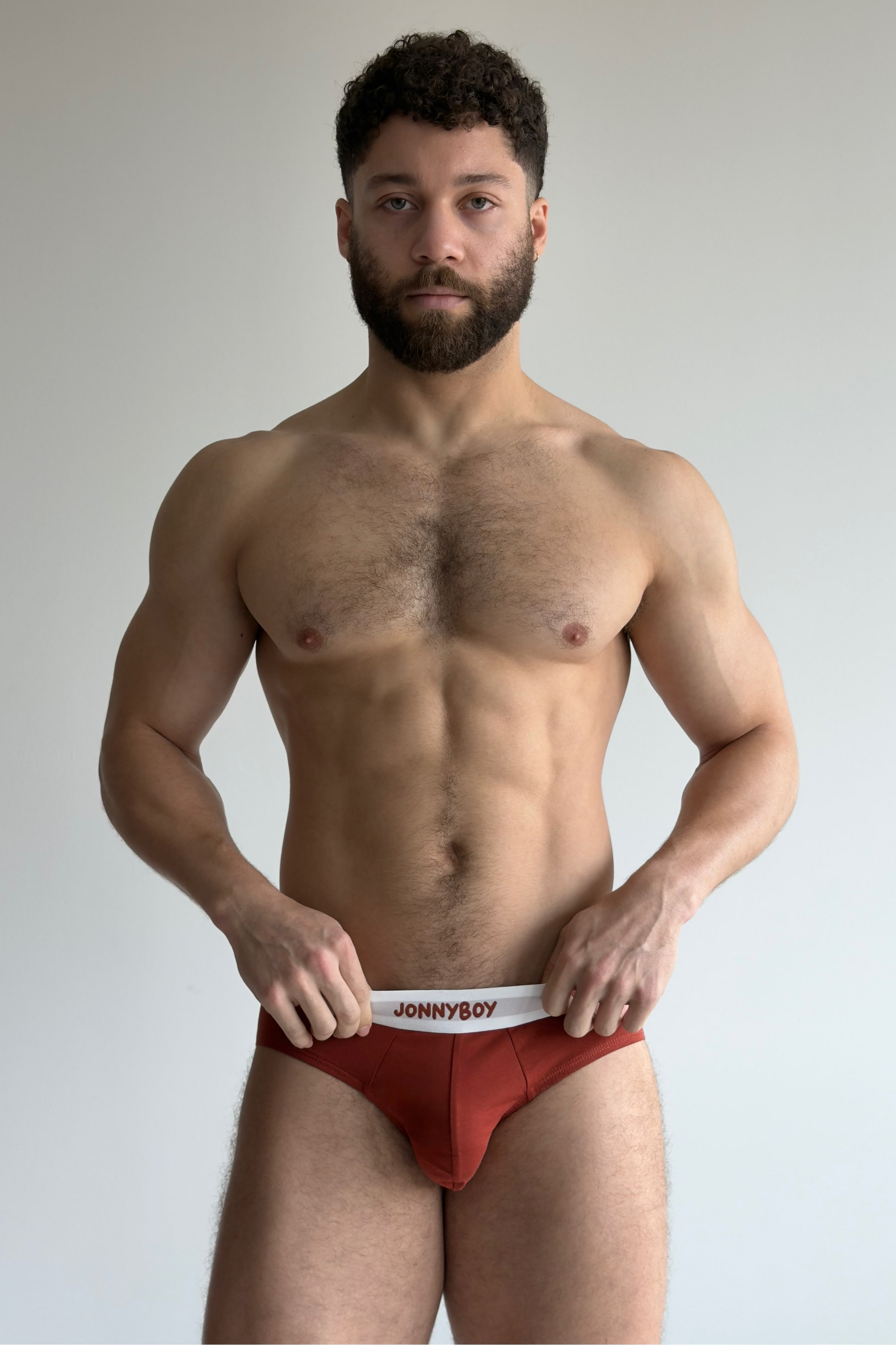 Man wearing a red swimsuit with 'Jonnyboy' branding against a plain background