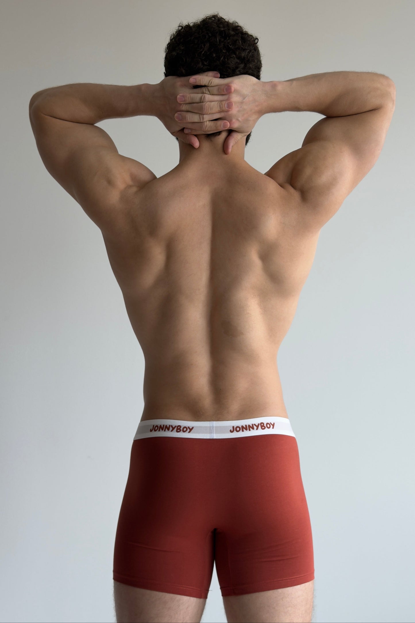 Person wearing red underwear with a brand logo on a plain background