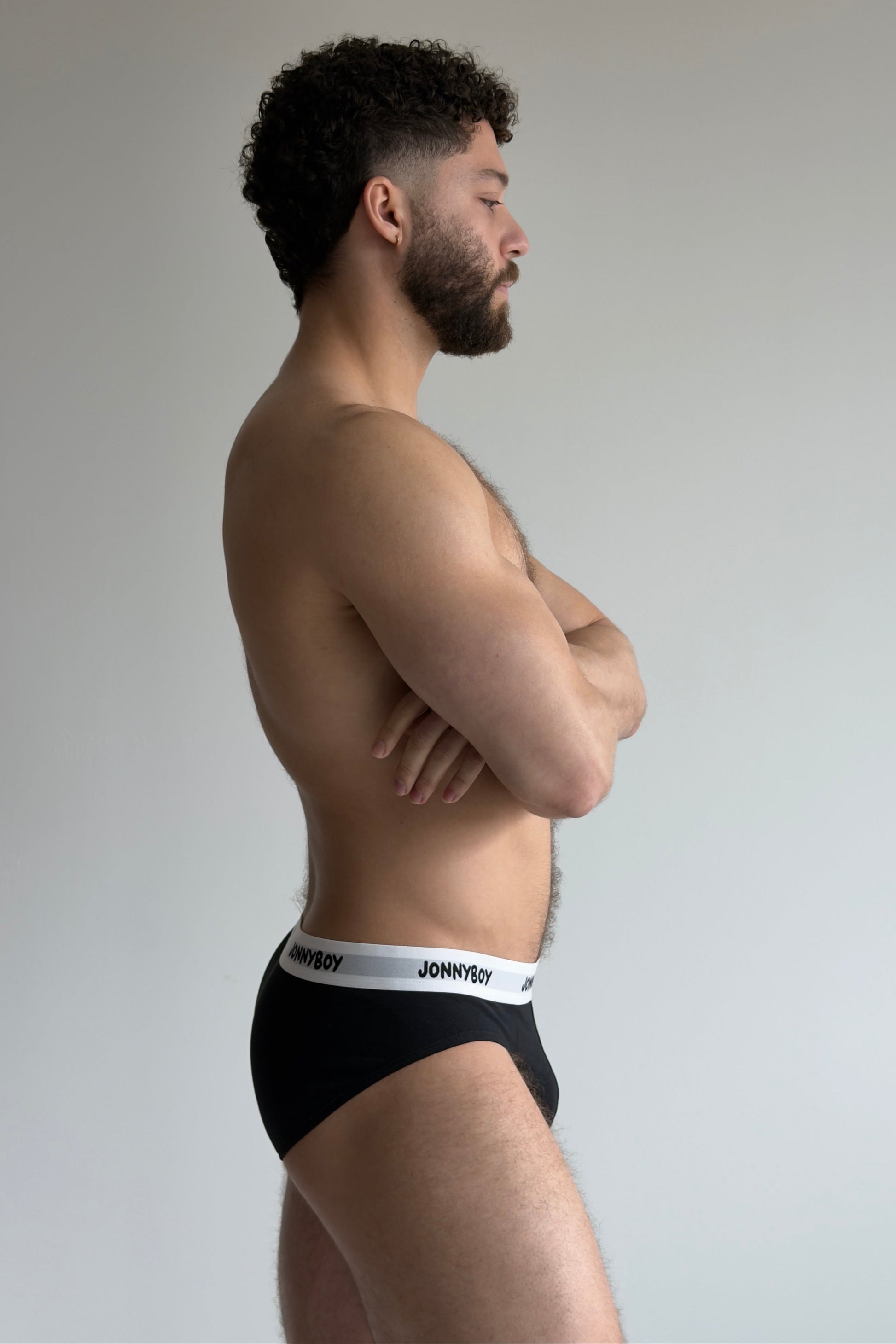 Man wearing black underwear with a white brand label on a plain background