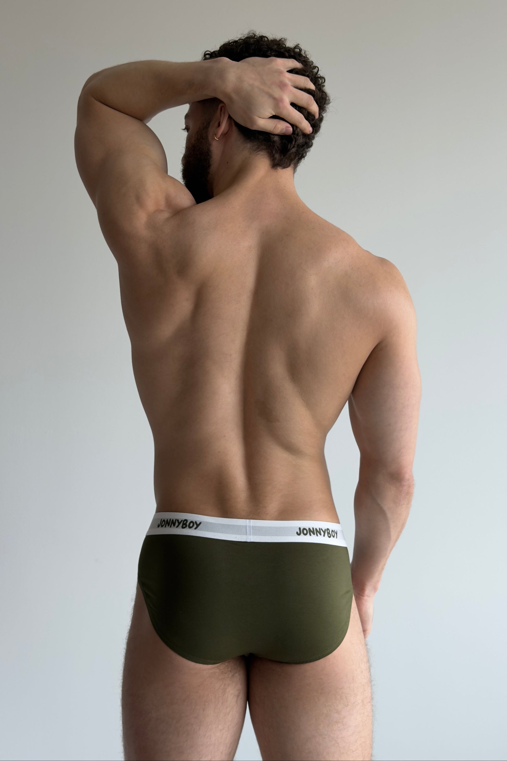 Man wearing green underwear with a white waistband on a plain background