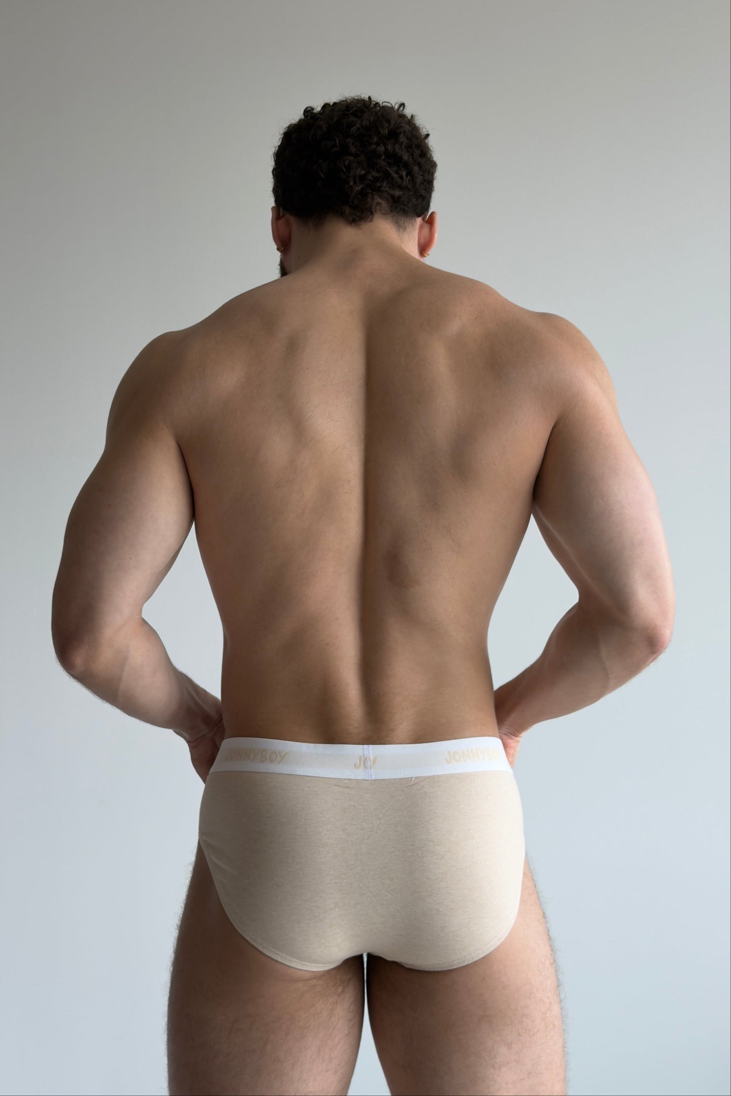 Man wearing beige underwear against a plain background