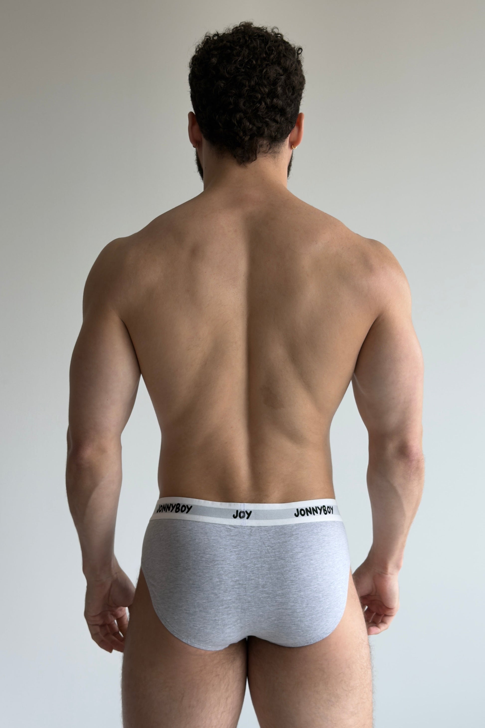 Man wearing white underwear with brand logo on a plain background